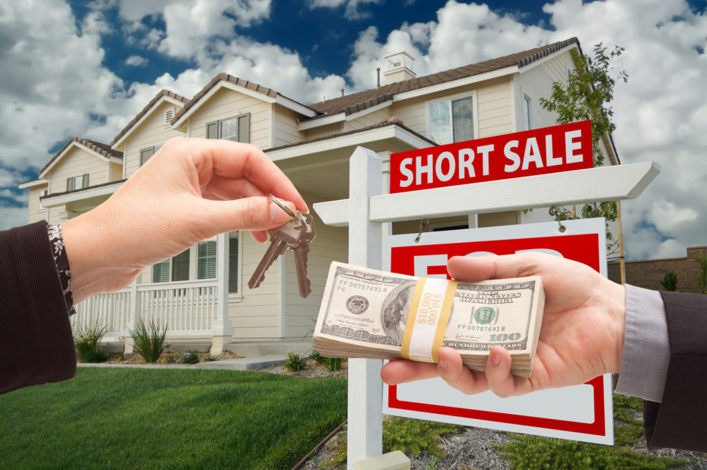 Handing Over Cash For House Keys and Short Sale Real Estate Sign in Front of Home.